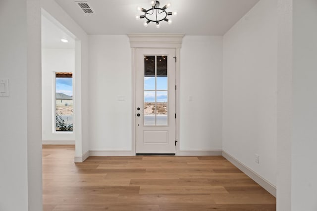 doorway to outside featuring an inviting chandelier and light hardwood / wood-style flooring