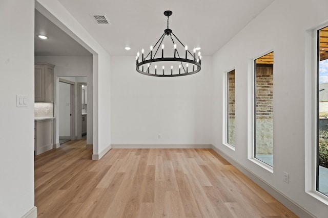 unfurnished dining area featuring light hardwood / wood-style floors and a chandelier