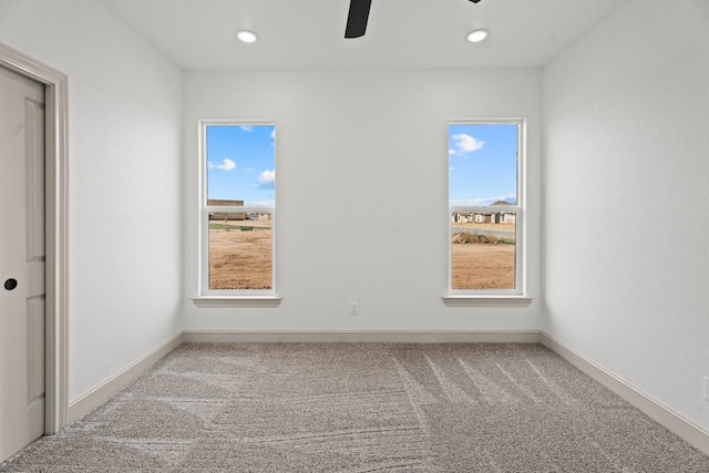 carpeted empty room with a wealth of natural light and ceiling fan