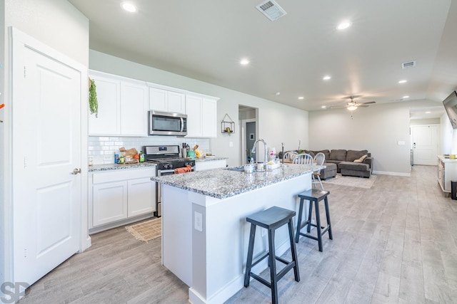 kitchen featuring stainless steel appliances, an island with sink, sink, and white cabinets