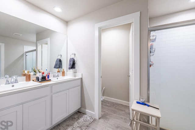 bathroom with hardwood / wood-style flooring, vanity, and a shower with shower door