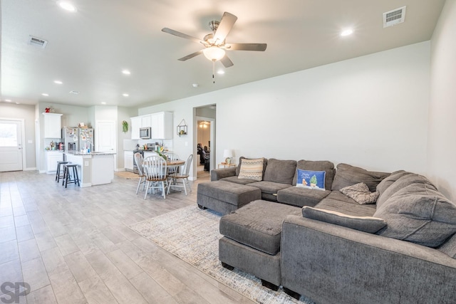 living room featuring ceiling fan and light hardwood / wood-style flooring