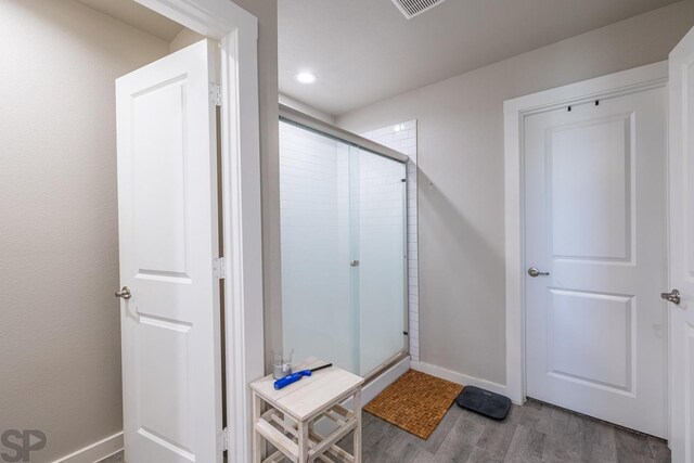 bathroom featuring hardwood / wood-style flooring and a shower with shower door