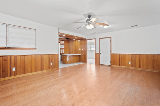 unfurnished room with ceiling fan, wooden walls, and light hardwood / wood-style floors