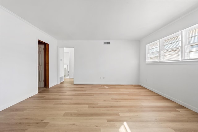 empty room with crown molding and light hardwood / wood-style flooring