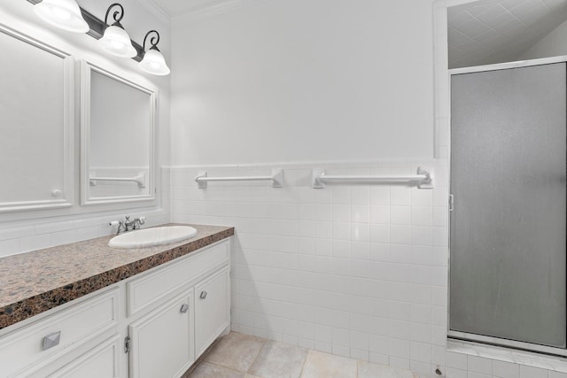 bathroom featuring a shower with shower door, crown molding, tile walls, vanity, and tile patterned flooring