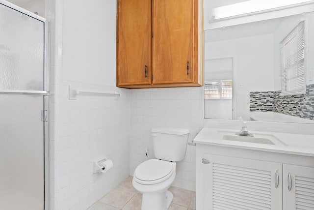 bathroom with toilet, tile walls, vanity, a shower with door, and tile patterned flooring