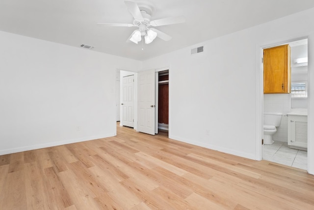 unfurnished bedroom featuring ceiling fan, tile walls, ensuite bathroom, light hardwood / wood-style floors, and a closet