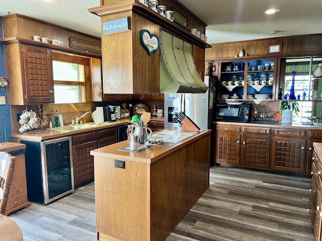 kitchen with sink, hardwood / wood-style flooring, wine cooler, a textured ceiling, and a kitchen island