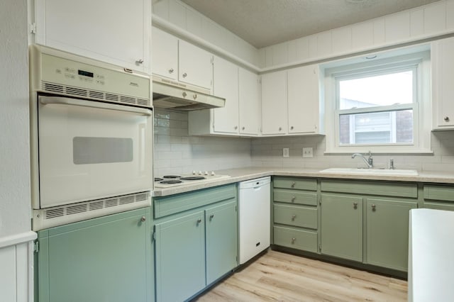 kitchen featuring sink, white appliances, light hardwood / wood-style flooring, and decorative backsplash