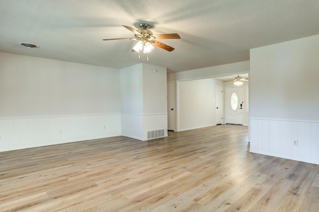 unfurnished room with ceiling fan, light hardwood / wood-style floors, and a textured ceiling