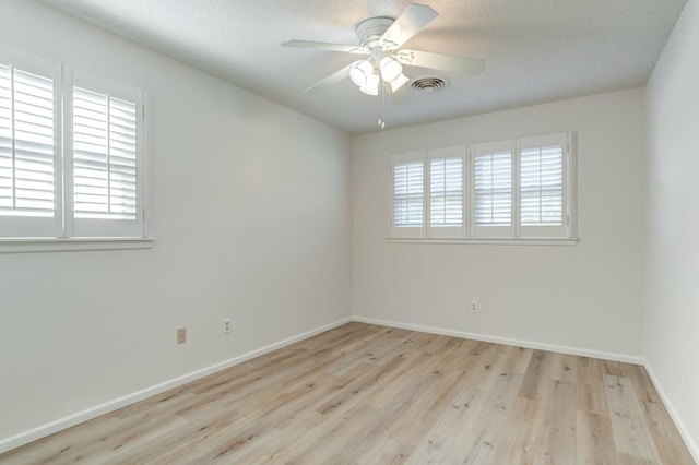 empty room featuring ceiling fan, a textured ceiling, light hardwood / wood-style flooring, and a healthy amount of sunlight