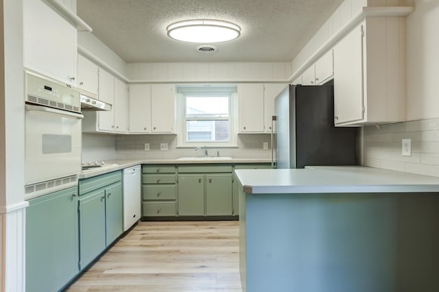 kitchen featuring sink, white appliances, white cabinetry, light hardwood / wood-style floors, and green cabinetry