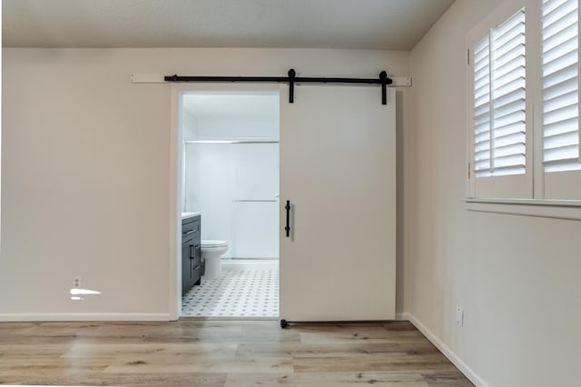 unfurnished room with a barn door and light hardwood / wood-style floors