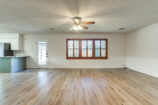 unfurnished living room with ceiling fan, light hardwood / wood-style flooring, and a textured ceiling