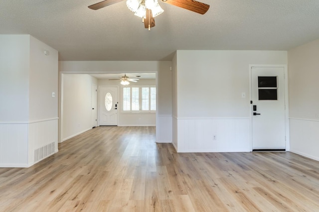 interior space featuring ceiling fan, a textured ceiling, and light hardwood / wood-style flooring