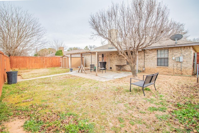 view of yard with a shed, an outbuilding, a fenced backyard, and a patio