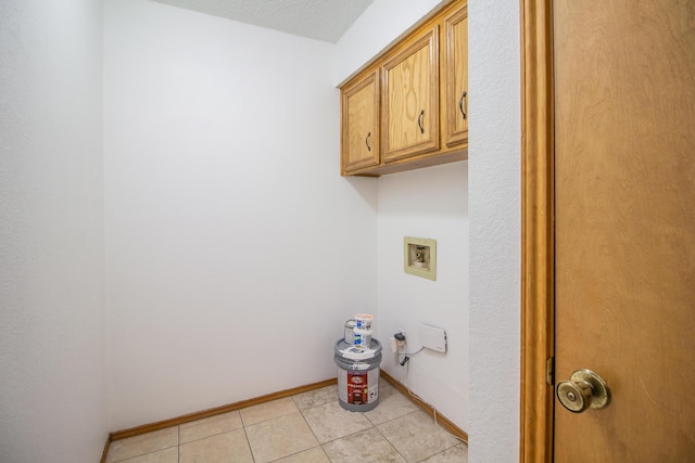 washroom with cabinet space, baseboards, light tile patterned floors, and washer hookup