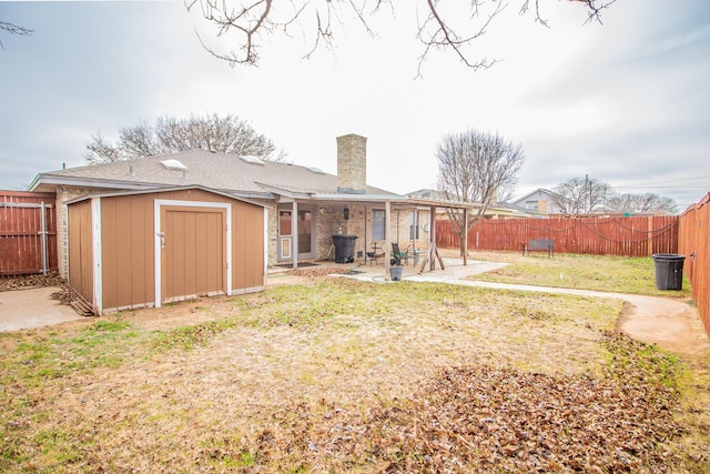 back of house with an outbuilding, a fenced backyard, a patio, and a storage unit