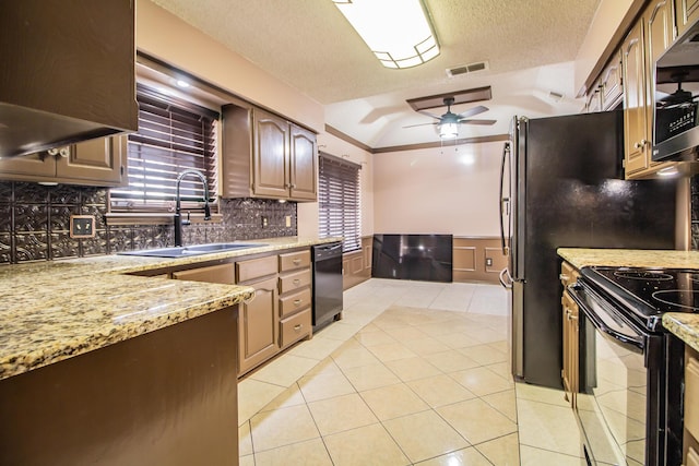 kitchen featuring light tile patterned floors, a sink, visible vents, wainscoting, and black appliances