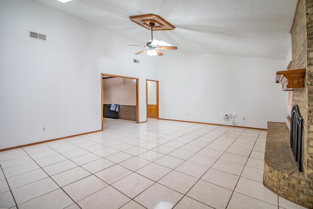 unfurnished living room with a textured ceiling, ceiling fan, light tile patterned flooring, a fireplace, and visible vents