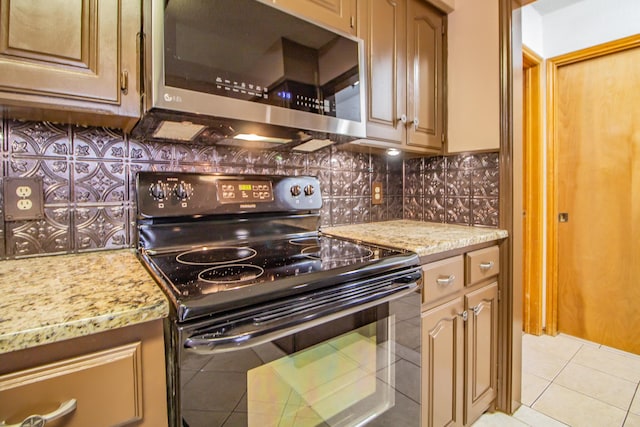 kitchen with stainless steel microwave, light stone countertops, black electric range, backsplash, and light tile patterned flooring