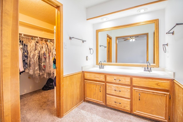 bathroom featuring double vanity, a wainscoted wall, a spacious closet, and a sink