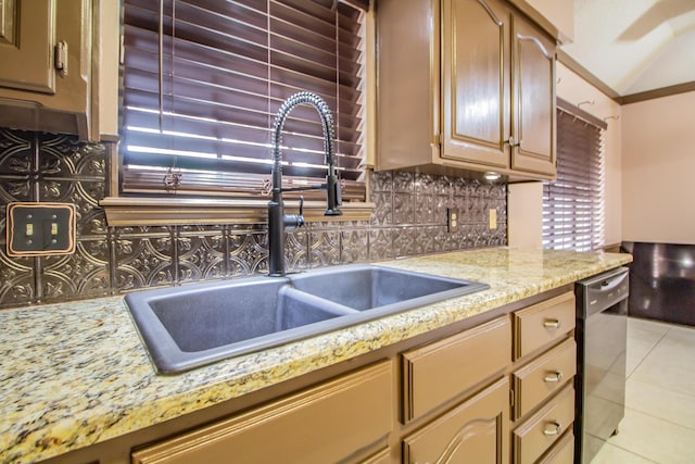 kitchen with light tile patterned floors, dishwasher, light stone counters, a sink, and backsplash