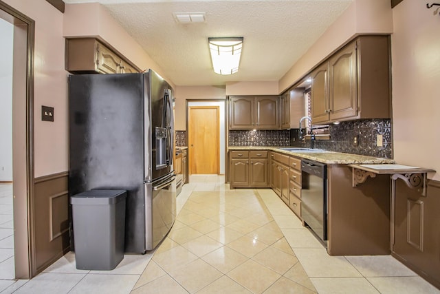 kitchen with stainless steel fridge with ice dispenser, dishwashing machine, a sink, backsplash, and light tile patterned flooring