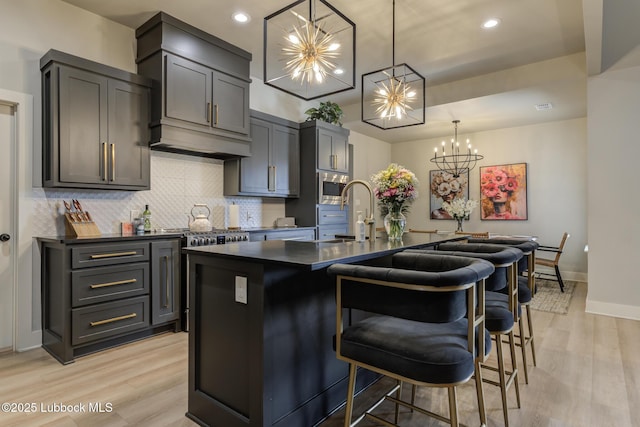 10907 Vicksburg Ave, Lubbock, TX 79424 - kitchen with stainless steel microwave, a chandelier, dark countertops, a sink, and light wood-style flooring