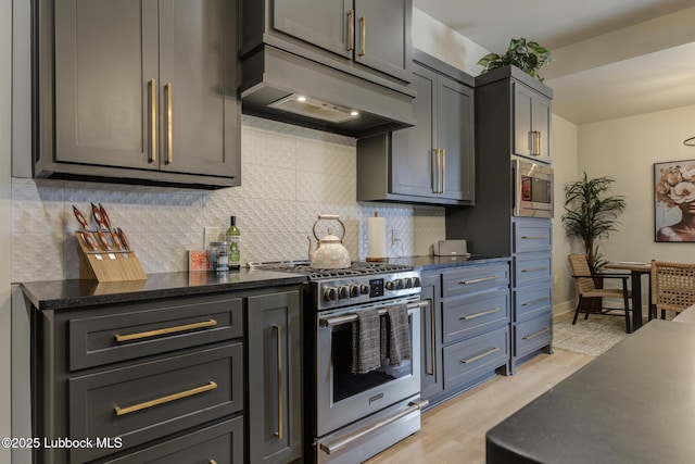 10907 Vicksburg Ave, Lubbock, TX 79424 - kitchen with appliances with stainless steel finishes, under cabinet range hood, light wood-type flooring, tasteful backsplash, and dark stone counters