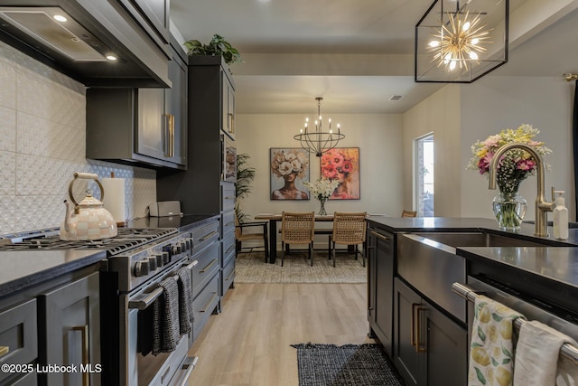 10907 Vicksburg Ave, Lubbock, TX 79424 - kitchen featuring stainless steel appliances, a chandelier, wall chimney exhaust hood, decorative backsplash, and dark countertops