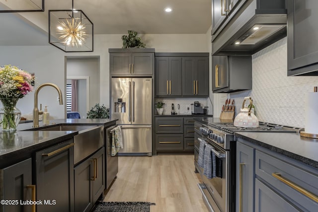 10907 Vicksburg Ave, Lubbock, TX 79424 - kitchen with stainless steel appliances, custom exhaust hood, backsplash, light wood-style floors, and dark stone countertops