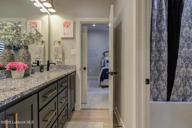 10907 Vicksburg Ave, Lubbock, TX 79424 - ensuite bathroom with double vanity, wood finished floors, baseboards, and a tub to relax in