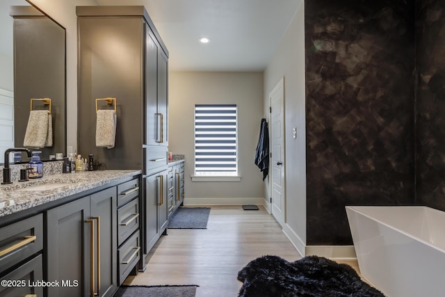 10907 Vicksburg Ave, Lubbock, TX 79424 - bathroom with wood finished floors, a freestanding tub, double vanity, baseboards, and recessed lighting