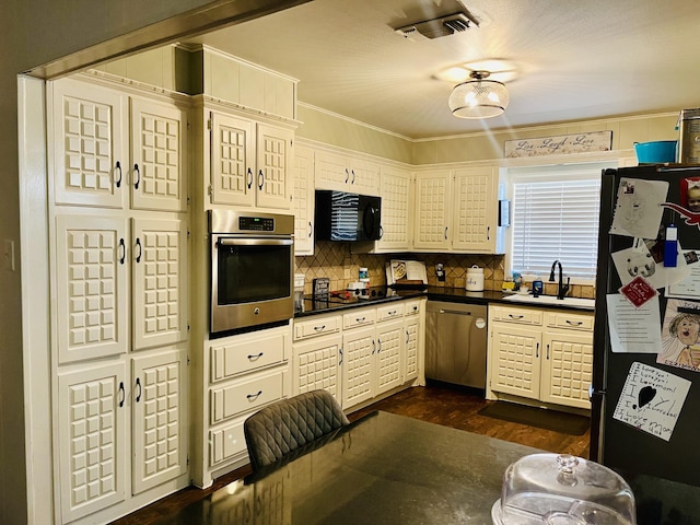 306 Parkwood Ln, Levelland, TX 79336 - kitchen featuring appliances with stainless steel finishes, dark countertops, tasteful backsplash, dark wood-style flooring, and ornamental molding