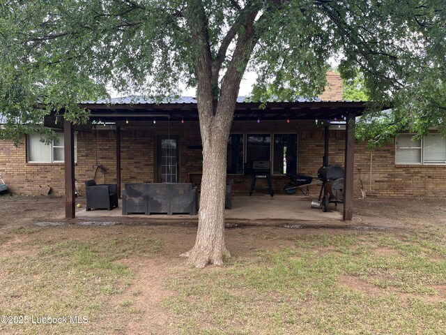 306 Parkwood Ln, Levelland, TX 79336 - rear view of property featuring a patio area, brick siding, a chimney, and an outdoor living space