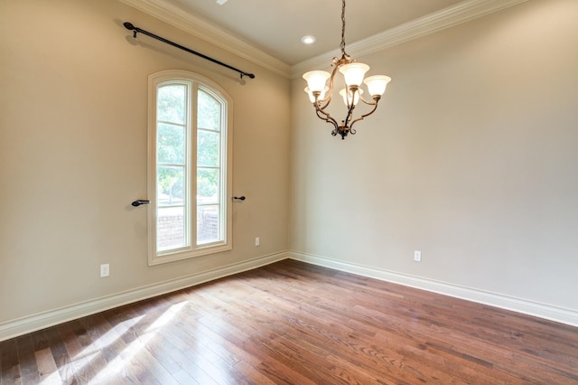 spare room featuring an inviting chandelier, wood-type flooring, and ornamental molding