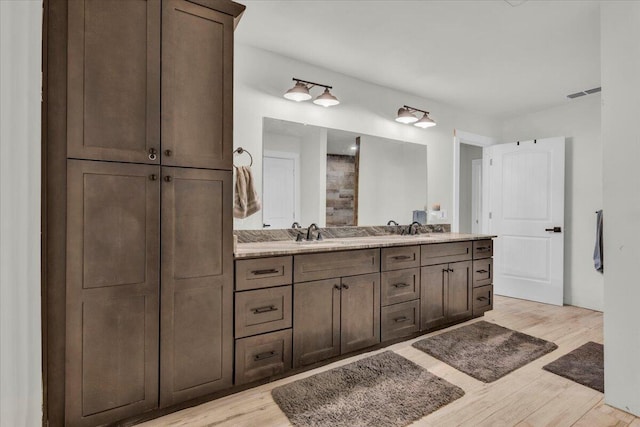 bathroom featuring double vanity, wood finished floors, visible vents, and a sink