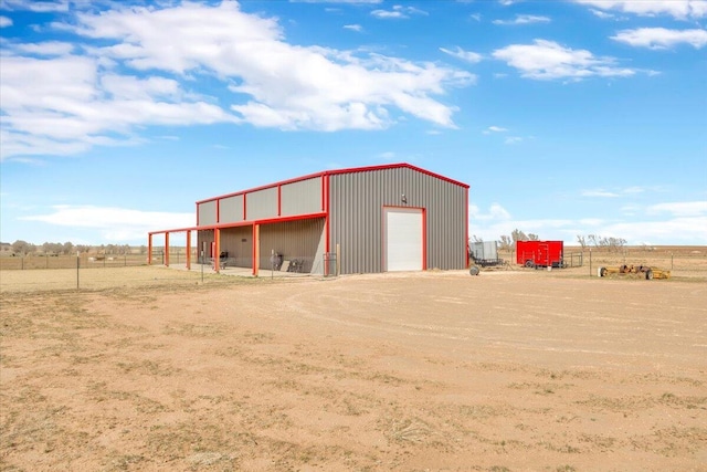 view of pole building featuring driveway and fence