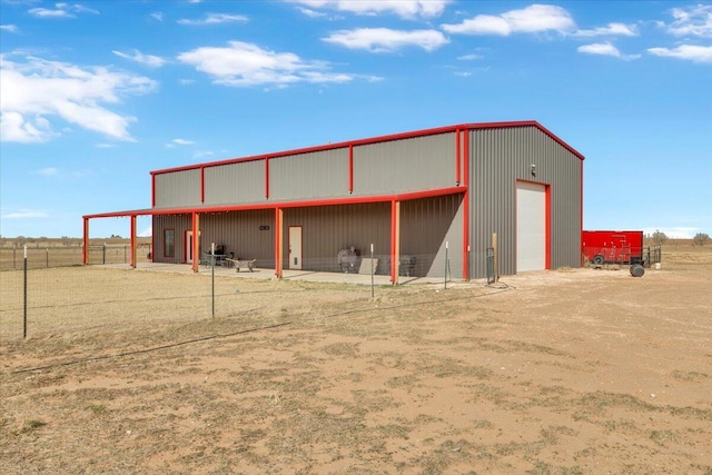 view of pole building featuring fence and dirt driveway