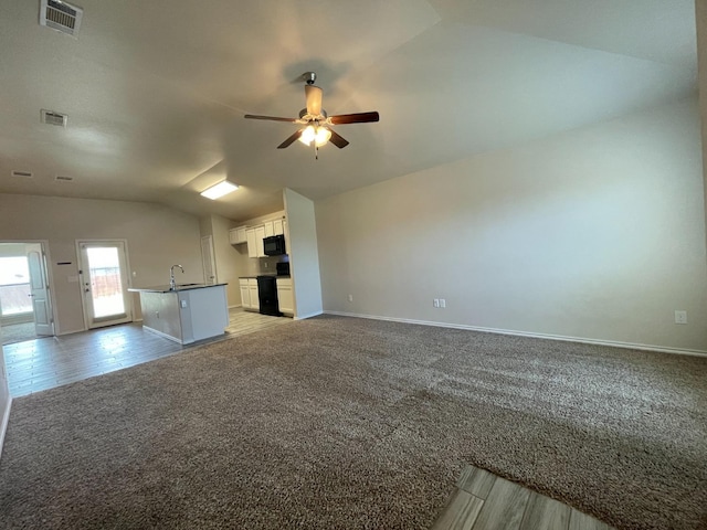 unfurnished living room with vaulted ceiling, sink, light carpet, and ceiling fan