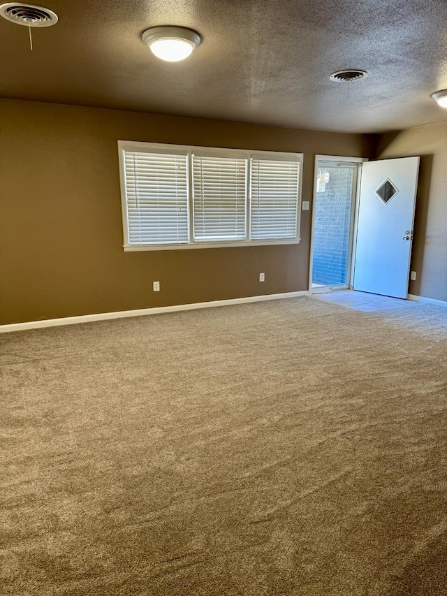 carpeted spare room with a textured ceiling