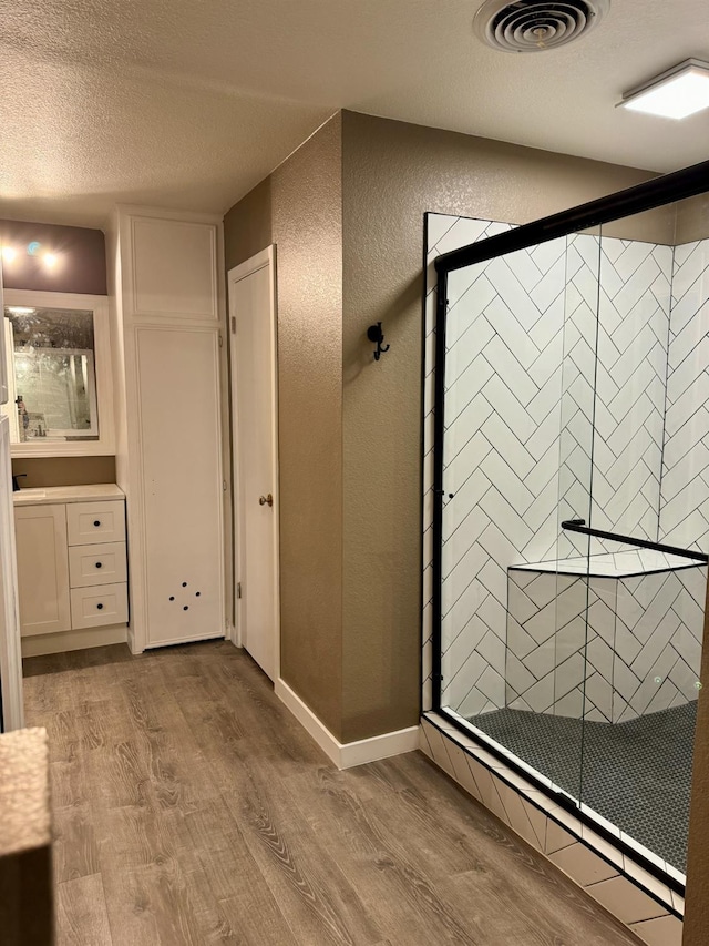 bathroom with an enclosed shower, hardwood / wood-style floors, vanity, and a textured ceiling