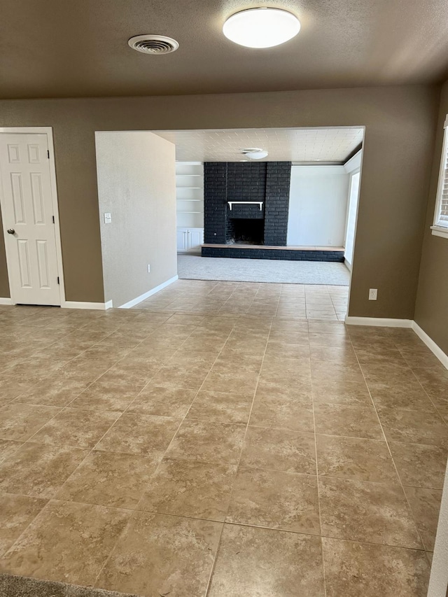 unfurnished living room featuring built in shelves, tile patterned floors, a fireplace, and a textured ceiling