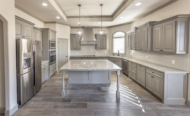 kitchen featuring sink, stainless steel appliances, a kitchen island, custom exhaust hood, and a raised ceiling