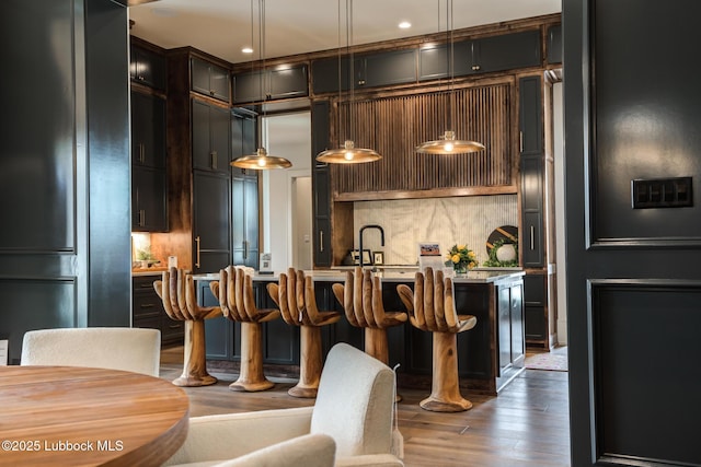 4510 Zadar Ave, Lubbock, TX 79407 - kitchen featuring decorative backsplash, light countertops, wood finished floors, hanging light fixtures, and a breakfast bar