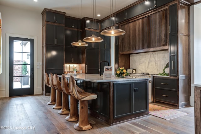 4510 Zadar Ave, Lubbock, TX 79407 - kitchen with gas stove, light wood finished floors, decorative light fixtures, a center island with sink, and a breakfast bar