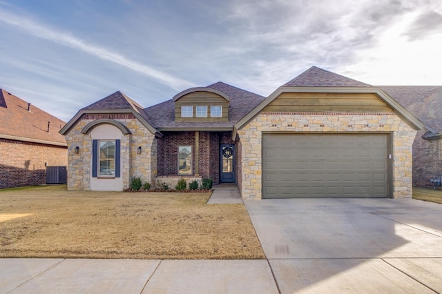 view of front facade with concrete driveway, roof with shingles, an attached garage, cooling unit, and a front yard