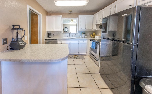 kitchen with sink, white cabinetry, stainless steel appliances, light tile patterned flooring, and decorative backsplash